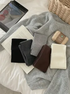 Gedetailleerd uitzicht op gezellige gebreide beenwarmers in diverse neutrale kleuren op zachte stof.