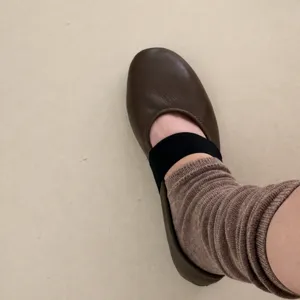Close-up detailopname van bruine lederen platte schoenen met zwarte band en geribbelde sokken.