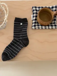 Vue détaillée de chaussettes rayées gris foncé en coton pour femmes avec bouton coquillage.