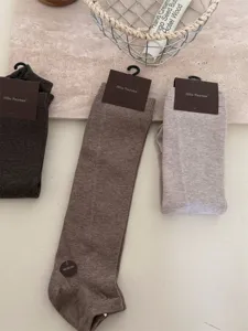 Gedetailleerd overzicht van comfortabele gebreide beenwarmers in neutrale bruine en grijze tinten.