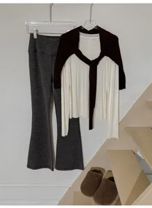 Ensemble de tenue minimaliste automne-hiver avec pantalon patte d'eph gris et haut blanc.
