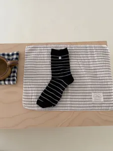 Vue détaillée de chaussettes en coton rayées noir et blanc avec un petit bouton coquillage.