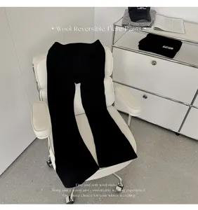 Gros plan détaillé du pantalon évasé en laine noire disposé sur une chaise moderne.