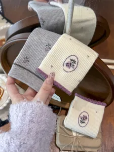 Gedetailleerde close-up van gezellige gebreide wintersokken met fijn geborduurd bloemdesign.