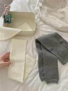 Detailopname van dikke gebreide winteroverknee-beenwarmers in zachte geribbelde textuur.