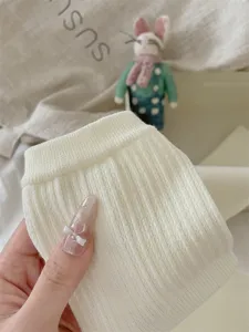 Detailopname van witte gebreide winterbeenwarmers, zachte geribbelde katoenen stof.