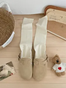 Cozy winter suede clogs paired with thick long knit socks, warm and comfortable footwear.