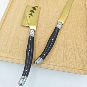 Elegante juego de cuchillo para mantequilla y untador de queso con mango negro y hoja dorada.