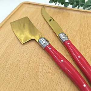 Cuchillo de queso con hoja dorada de acero inoxidable y mango rojo para mantequilla y tostadas.