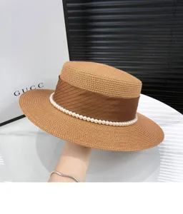Summer wide brim straw hat with brown ribbon and pearl decoration for women UV protection.