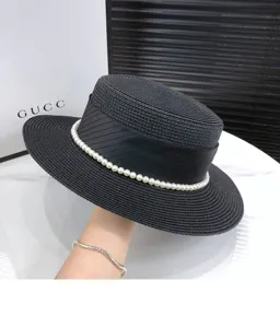 Detail view of black flat straw hat with pearl decoration and elegant ribbon for summer sun.