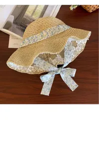 Close-up view of the straw hat featuring blue floral ribbon and delicate white lace trim.