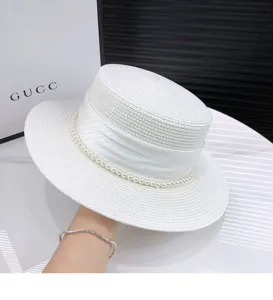 Detailed view of women's white flat top straw hat with pearl band and ribbon for summer.