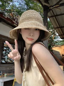 Detailed close-up of the woven straw bucket hat, highlighting fine texture and summer beach style.