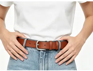 Primo piano di un'elegante cintura in pelle marrone con fibbia argentata sui jeans.