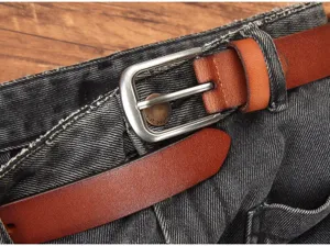 Close-up detail van bruine dames leren riem met metalen gesp gedragen op stijlvolle zwarte jeans.