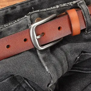 Klassieke bruine echt lederen riem met zilveren doorngesp gestyled op donkere denim jeans vrouwen.