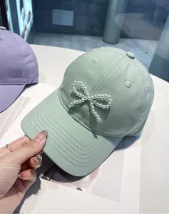 Green baseball cap with pearl bow detail, soft crown sun hat, fashionable casual women hat.
