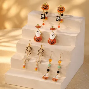 Halloween asymmetrische oorbellen met pompoen, spook en kralen kwastjes details.