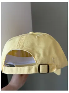Adjustable yellow cotton baseball cap detail view, classic curved brim and metal buckle.