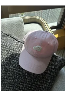Pink baseball cap front embroidery detail showing curved brim and fine texture closeup view.