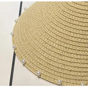 Detailaufnahme des Sommer-Strohhutes mit Perlenbesatz, offener Strand-Sonnenschutz.