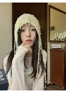 Detail shot of beige crochet pearl tassel headscarf, exquisite hollow knit bonnet hat closeup.