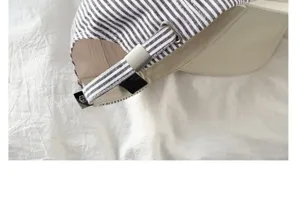 Close-up detail shot of the adjustable metal buckle and striped strap on a stylish casual cap.