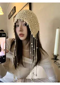 Close-up detail of the handmade beige crochet pearl tassel cap, showcasing delicate weaving.