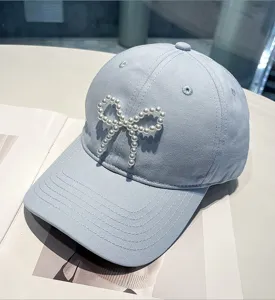 Light blue baseball cap featuring an elegant pearl bow detail for women, soft top design.