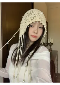 Detailed shot of a beige crochet pearl tassel beanie showing the hollow knit texture and design.