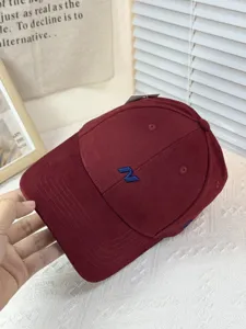 Detailansicht der burgunderroten Cord-Baseballkappe mit blauer Stickerei und fester Krone.