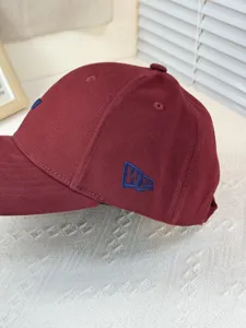 Detailansicht der bordeauxroten Baseballcap mit blauer Stickerei und steifem Kronendesign.