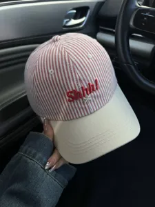 Detail view of stylish red and white striped baseball cap with cute Shhh embroidery and curved brim.