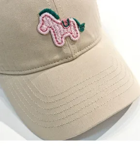 Dettaglio in primo piano di cappellino da baseball beige con ricamo di pony rosa per sole.