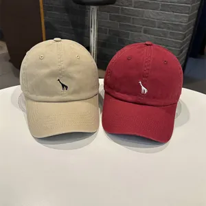 Nahaufnahme von modischen Baseballcaps mit süßer Giraffenstickerei und feinen Stoffdetails.
