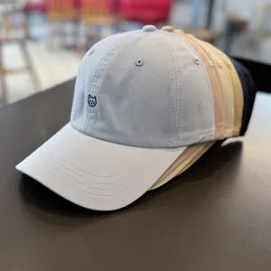 Detail view of stacked baseball caps in multi-colors featuring cute cat embroidery on soft cotton fabric.