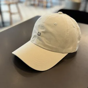 Detail shot of beige baseball cap featuring cute cat embroidery on front, curved brim design.