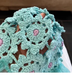 Close-up of handmade crochet lace bucket hat detail, showing hollow floral pattern design.