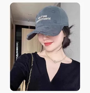 Détail de casquette de baseball grise usée, design brodé de texte, style streetwear décontracté.