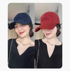 Détail de la casquette de baseball brodée usée en bleu marine et rouge portée par mannequin.
