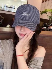 Close-up detail of the stylish plaid embroidered baseball cap in an indoor cafe setting.