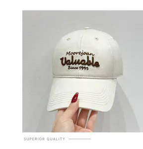 Detailed view of the beige cotton baseball cap featuring stylish brown embroidery on the front.