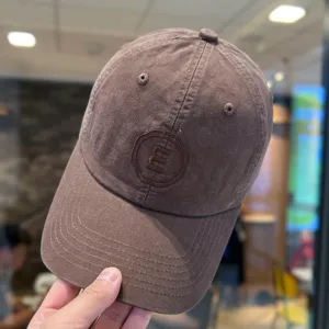 Detailaufnahme der braunen Cord Baseballkappe mit gesticktem Logo und weicher Krone.