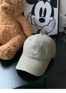 Detailed view of green plaid baseball cap with white cursive embroidery, close up hat fabric.