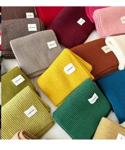 Close-up detail of cozy solid color knitted winter scarves in various vibrant shades.
