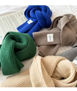 Cozy knit winter scarf detail featuring ribbed texture, soft material, and stylish woven label.