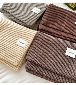 Cozy knitted scarf in thick solid color design with label detail for autumn and winter warmth.