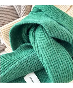Detailed view of the thick knitted green scarf texture, cozy winter accessory close-up.
