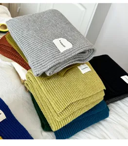 Detailed view of cozy knit winter scarves stacked in assorted solid colors for cold weather.